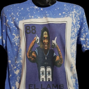 May include: A blue t-shirt with white splatter paint and a printed image of a football player with the number 88 on his jersey. The image is in a card-like frame with the text "EL LAMB" at the bottom.