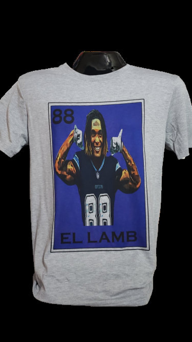 May include: A gray t-shirt with a blue and white graphic of a football player with the number 88 on his jersey. The graphic is in the style of a Loteria card and says "EL LAMB" at the bottom.