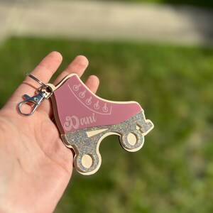 May include: A pink roller skate keychain with glitter accents and the name "Dani" engraved on the side.