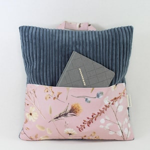 Könnte beinhalten: Ein blaues Cordkissen mit einer rosa Blumentasche. In der Tasche befindet sich ein graues Notizbuch mit dem Aufdruck "Lifestyle" auf dem Einband.