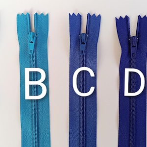 Puede incluir: Se muestran cinco cremalleras de diferentes colores en vertical, cada una con una letra blanca al lado. Los colores van del azul claro al azul marino. Las letras son A, B, C, D y E. Las cremalleras están cerradas.