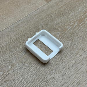 Puede incluir: Caja de plástico blanco con una abertura rectangular. La caja tiene un acabado liso y mate.