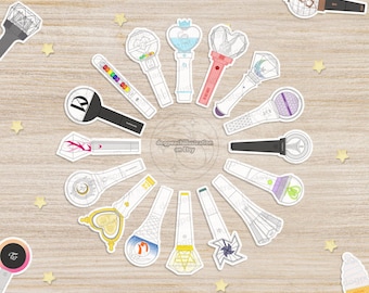 May include: A selection of illustrated light stick stickers in a circular arrangement on a light wood-effect surface. The stickers showcase diverse designs, including hearts, stars, and geometric shapes. Some stickers have text.