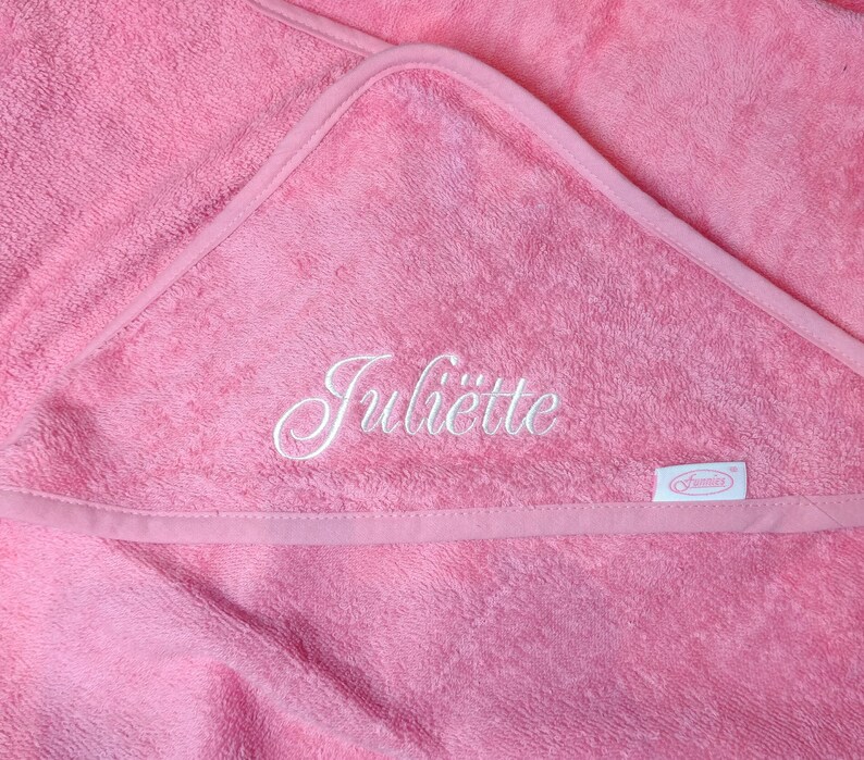May include: Pink hooded towel with the name "Juliette" embroidered in white. The towel has a white label with the word "Summer" on it.