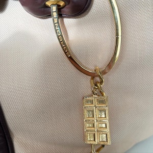 May include: A gold-toned key chain with a rectangular charm featuring a grid pattern. The key chain is attached to a gold-toned ring with the word "EGOIST" engraved on it.