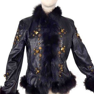 K&ouml;nnte beinhalten: Eine schwarze Lederjacke mit einem Kunstfellkragen und -&auml;rmelaufschl&auml;gen. Die Jacke ist mit goldfarbenen Nieten und Nieten verziert.