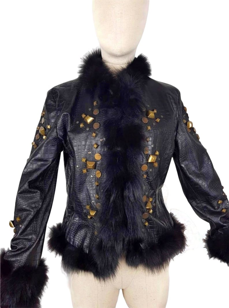 K&ouml;nnte beinhalten: Eine schwarze Lederjacke mit einem Kunstfellkragen und -&auml;rmelaufschl&auml;gen. Die Jacke ist mit goldfarbenen Nieten und Nieten verziert.