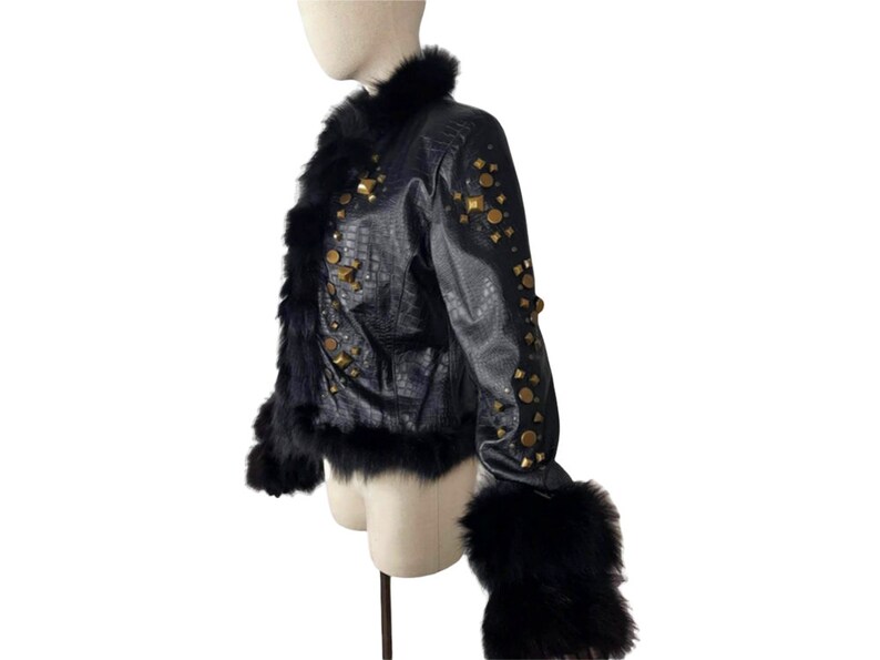 K&ouml;nnte beinhalten: Eine schwarze Lederjacke mit Pelzkragen und -&auml;rmeln. Die Jacke ist mit goldfarbenen Nieten verziert.