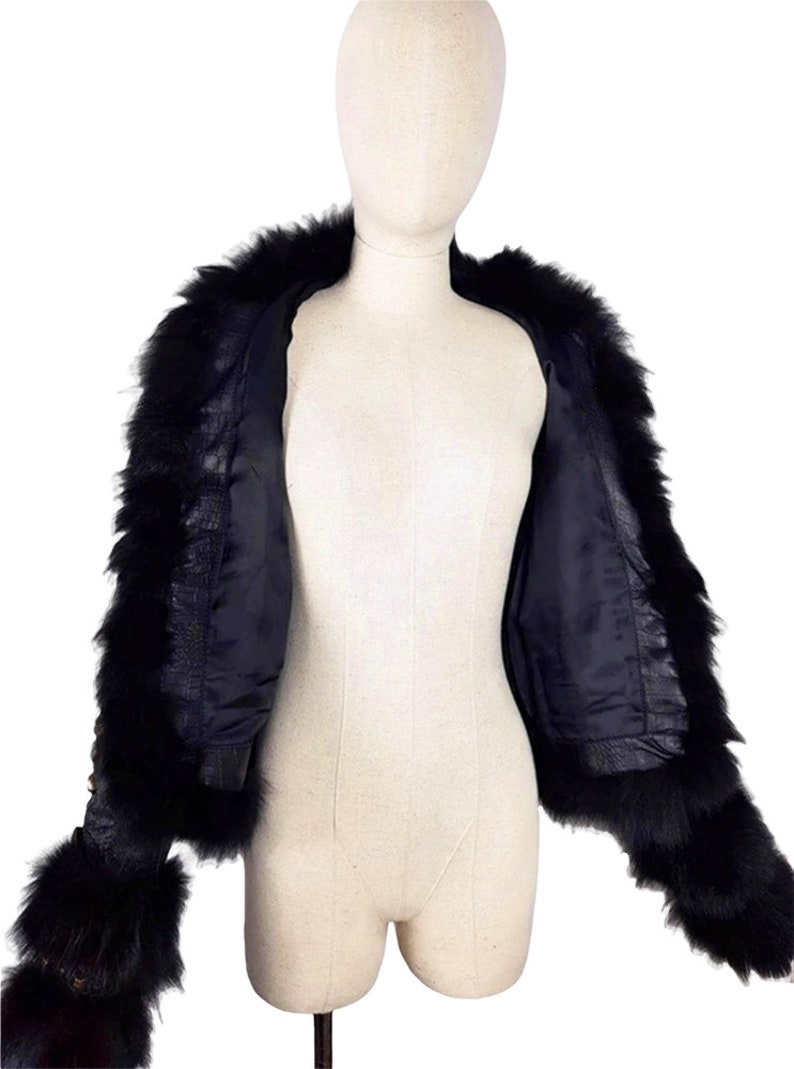 K&ouml;nnte beinhalten: Eine schwarze Kunstfelljacke mit Rei&szlig;verschluss und langen &Auml;rmeln. Die Jacke hat einen Pelzkragen und Pelzmanschetten.