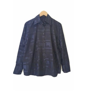 May include: A dark blue long-sleeved button-down shirt with a geometric pattern.