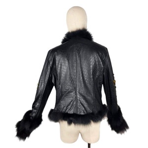 K&ouml;nnte beinhalten: Schwarze Kunstlederjacke mit Pelzkragen und -&auml;rmelaufschl&auml;gen. Die Jacke hat ein Kroko-Pr&auml;gemuster.