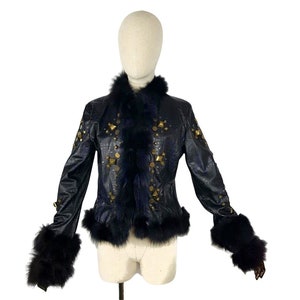 K&ouml;nnte beinhalten: Eine schwarze Lederjacke mit goldenen Nieten und einem schwarzen Pelzkragen und -&auml;rmeln.