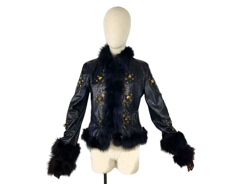 K&ouml;nnte beinhalten: Eine schwarze Lederjacke mit goldenen Nieten und einem schwarzen Pelzkragen und -&auml;rmeln.