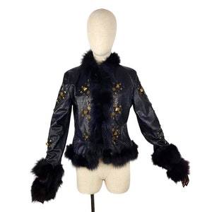 K&ouml;nnte beinhalten: Eine schwarze Lederjacke mit goldenen Nieten und einem schwarzen Pelzkragen und -&auml;rmeln.
