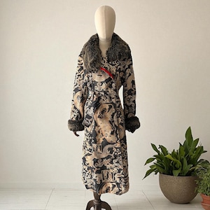 May include: A long, patterned coat with a faux fur collar and cuffs. The coat features a black and tan dragon design with a red accent. The coat is displayed on a mannequin.