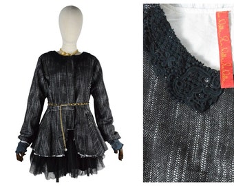 May include: A black and white striped jacket with a black lace collar and a gold chain belt. The jacket has a ruffled hem and is layered over a black tulle skirt.