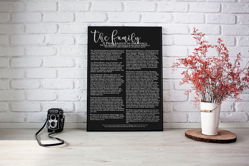 K&ouml;nnte beinhalten: Ein schwarz-wei&szlig;es Poster mit dem Text "The Family: A Proclamation to the World" und einer Liste von Prinzipien &uuml;ber die Familie. Das Poster h&auml;ngt an einer wei&szlig;en Backsteinwand.