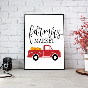 May include: A white sign with black text that reads "farmers market" and a red pickup truck with orange pumpkins in the bed.