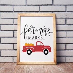 May include: A framed print with a red pickup truck carrying pumpkins and the text "farmers market" in black script.