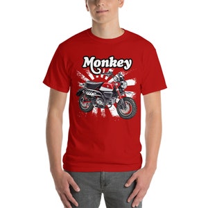 Könnte beinhalten: Rotes T-Shirt mit einer weißen Grafik einer roten und schwarzen Motorrad mit dem Wort "Monkey" in weiß darüber. Das Motorrad ist vor einem weißen und roten japanischen Sonnenaufgang-Motiv platziert.