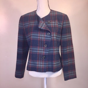May include: A blue, red, and green plaid blazer with a single-breasted closure and four buttons. The blazer has a slightly asymmetrical collar and long sleeves.