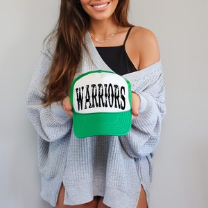 May include: A green and white trucker hat with the word "WARRIORS" in black lettering.