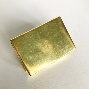 Pode incluir: Uma pequena caixa retangular de lat&atilde;o com uma cruz gravada na parte superior.