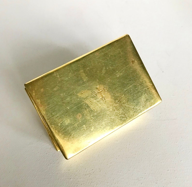 Pode incluir: Uma pequena caixa retangular de lat&atilde;o com uma cruz gravada na parte superior.