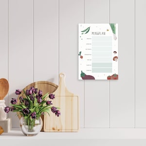 Könnte beinhalten: Ein weißer, druckbarer Speiseplan mit grünem und weißem Rand. Der Planer hat einen Titel, der "MENÜPLAN" lautet, und bietet Platz für jeden Tag der Woche: Montag, Dienstag, Mittwoch, Donnerstag, Freitag, Samstag und Sonntag. Der Planer ist mit bunten Illustrationen von Gemüse und Obst verziert.
