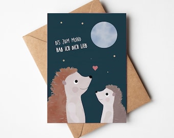May include: A greeting card with a dark blue background featuring two hedgehogs looking up at a blue moon. The text on the card reads "Bis zum Mond hab ich dich lieb".