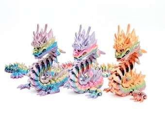 May include: Three colorful dragon figurines with iridescent scales and a rainbow gradient. The dragons are in a curled up position with their heads facing forward.