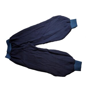 Könnte beinhalten: Eine dunkelblaue, weite Hose mit elastischen Bund und Bündchen. Die Hose ist aus einem weichen, strukturierten Stoff.