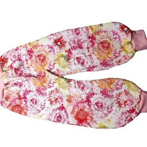 Könnte beinhalten: Rosa-weiße Hose mit einem bunten Blumenmuster. Die Hose hat einen rosa elastischen Bund und Bündchen.