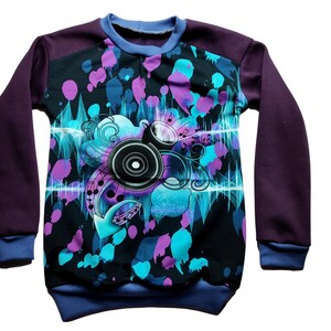 Könnte beinhalten: Ein langärmliges Sweatshirt mit einem schwarzen, blauen und violetten Grafikdruck eines Lautsprechers mit Musiknoten und einem Sprühfarben-Design. Das Sweatshirt hat einen violetten Körper und blaue Ärmel.