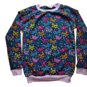Könnte beinhalten: Ein langärmliger marineblauer Pullover mit einem bunten Schmetterlingsdruck. Die Schmetterlinge sind in den Farben Pink, Gelb, Orange und Blau gehalten.