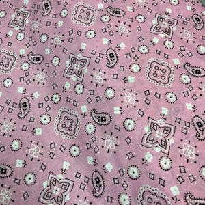 May include: Pink fabric with a white and black paisley pattern.