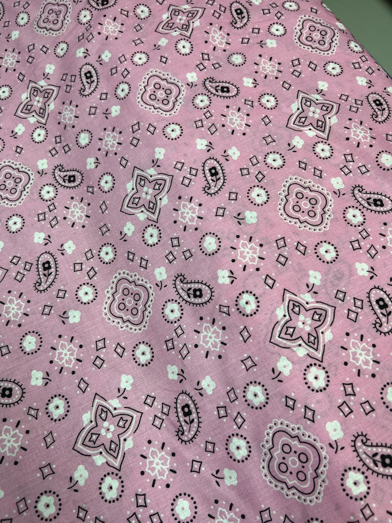 May include: Pink fabric with a white and black paisley pattern.