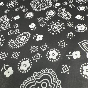 May include: Black fabric with a white paisley pattern. The pattern includes paisley shapes, diamonds, and small flowers.