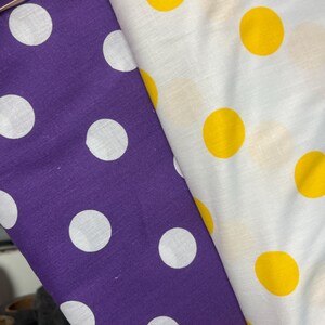 Puede incluir: Dos telas con estampado de lunares. Una es morada con lunares blancos, la otra blanca con lunares amarillos. Las telas est&aacute;n dobladas una sobre otra, mostrando los diferentes patrones y colores.