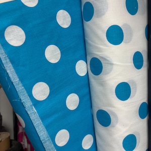 Puede incluir: Dos rollos de tela, uno en azul turquesa vibrante con grandes lunares blancos, y el otro en blanco con lunares turquesa. La tela est&aacute; enrollada, mostrando el dise&ntilde;o repetitivo. Ideal para proyectos de costura.