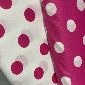 Puede incluir: Dos telas con un estampado de lunares. Una tela es blanca con grandes lunares magenta. La otra tela es magenta con grandes lunares blancos. Las telas est&aacute;n dobladas y superpuestas.