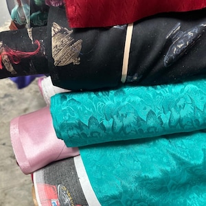 Puede incluir: Un rollo de tela rojo, un rollo negro con una franja blanca, un rollo turquesa con estampado floral, un rollo rosa y un rollo con estampado colorido.