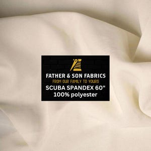 May include: Cream-colored fabric with a rippled texture. A black rectangle displays the text "FATHER & SON FABRICS" and "SCUBA SPANDEX 60"" with "100% polyester" below. The fabric is likely used for clothing or upholstery.