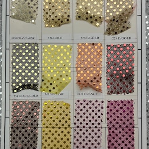 May include: A swatch card with 10 different fabric samples. The fabric is a sheer mesh with gold polka dots. The colors of the fabric samples are champagne, gold, orange, pink, black, yellow, and brown.