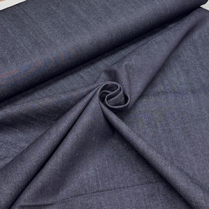 May include: Close-up of a dark blue fabric with a subtle sheen. The fabric is folded and draped, creating soft shadows and highlighting the texture. The material appears to be a medium-weight textile, suitable for apparel or home decor.