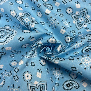 May include: Blue fabric with a white and black bandana print. The fabric is folded and shows the pattern.