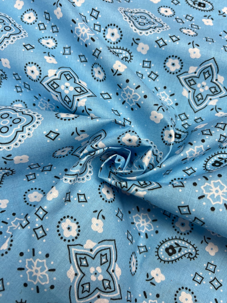 May include: Blue fabric with a white and black bandana print. The fabric is folded and shows the pattern.
