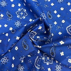 May include: Blue fabric with a white and black paisley pattern. The fabric is folded in half and the pattern is visible on both sides.