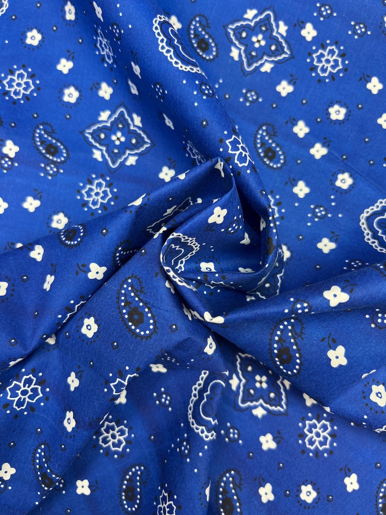 May include: Blue fabric with a white and black paisley pattern. The fabric is folded in half and the pattern is visible on both sides.