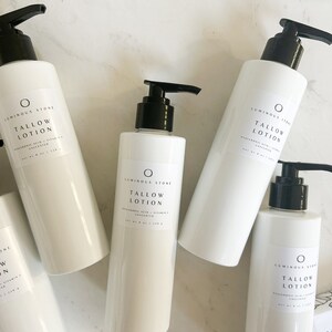 May include: Four white bottles of unscented tallow lotion with black pump tops. The bottles are labeled "LUMINOUS STONE TALLOW LOTION HYALURONIC ACID + VITAMIN E UNSCENTED NET WT 8 OZ / 236 g"